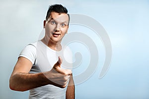 Portrait of a man on a light background, shows a thumbs up, puts a like. The concept of body language, human emotions, reaction