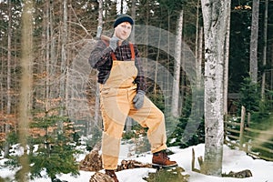 Portrait of a man lumberjack with an ax in his hands on a background of forest and trees