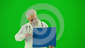 Portrait of man medic on chroma key green screen. Close up senior doctor in white coat holding advertisement board and