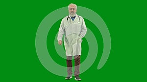 Portrait of man medic in studio on chroma key green screen. Senior doctor in white uniform walking looking at the camera