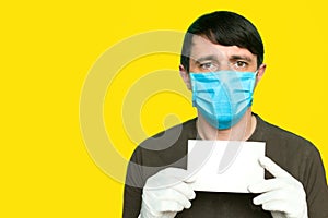 Portrait of an man in a medical mask and gloves. He is holding a clear piece of paper. Coronavirus with blankspace. Coronavirus