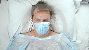 portrait of a man in a medical mask lying on a bed in a hospital