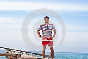 Portrait of a man with a middle beard in a shirt and red shorts on a traditional fisherman boat