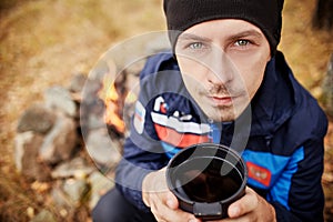 Portrait of a Man with a mug of hot tea in his hands fall in a forest fire. A picnic in forest