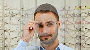 Portrait of man in new glasses in optical store