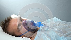 portrait of a man in an oxygen mask who lies on a bed in a hospital