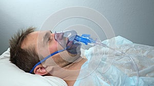 portrait of a man in an oxygen mask who lies on a bed in a hospital