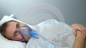 portrait of a man in an oxygen mask who lies on a bed in a hospital