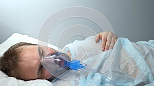 portrait of a man in an oxygen mask who lies on a bed in a hospital