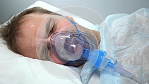 portrait of a man in an oxygen mask who lies on a bed in a hospital