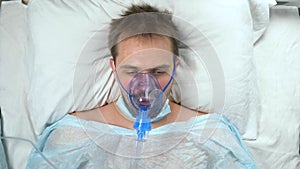 portrait of a man in an oxygen mask who lies on a bed in a hospital