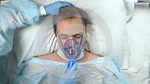 portrait of a man in an oxygen mask who lies on a bed in a hospital