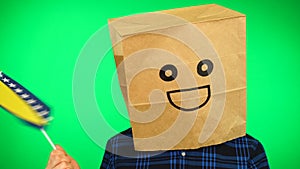 Portrait of man with paper bag on head waving Bosnia and Herzegovina flag with smiling face against green background.