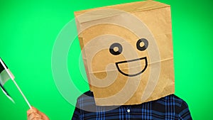 Portrait of man with paper bag on head waving Estonian flag with smiling face against green background.