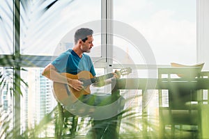 Portrait Of Man Playing Classic Guitar And Singing At Home