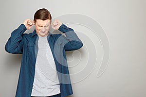 Portrait of man plugging ears with fingers, suffering from loud sounds