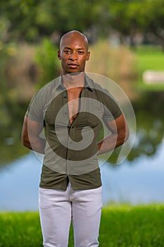 Portrait of man posing with hands behind his back. Guy is wearing a button shirt with shite pants