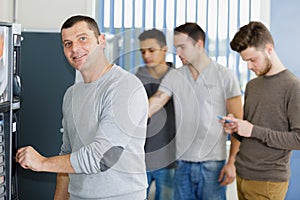 portrait man putting coin into vending machine