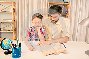 Portrait of man reading book to his little son