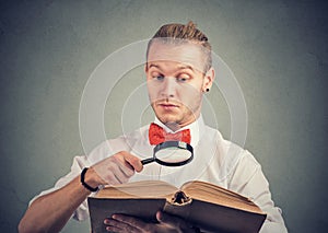 Portrait of a man reading an interesting book with magnifying glass