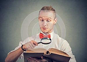 Portrait of a man reading an interesting book with magnifying glass photo