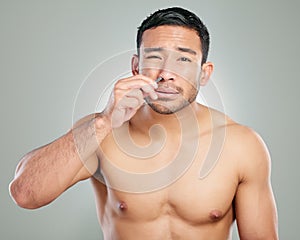 Portrait, man and remove nose hair for beauty, grooming routine and pamper treatment on grey studio background. Face photo