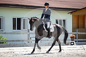 Man rider and black stallion horse galloping during equestrian dressage competition