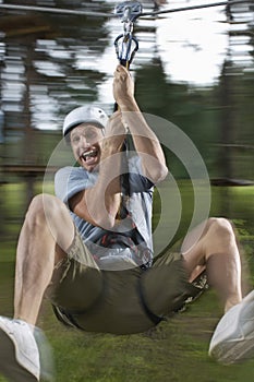 Portrait of Man riding zip-line in forest