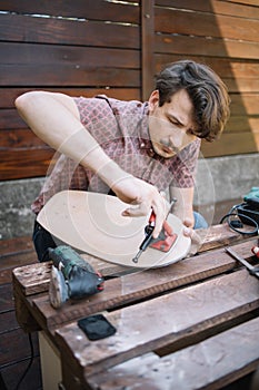 Portrait of man screwing skateboard trucks on wooden deck