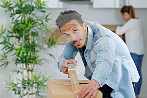 portrait man sealing cardboard box with brown tape