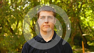 Portrait of man with serious concentrated face looking into the camera outdoors. Close up shot.