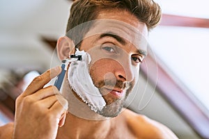 Portrait, man and shaving beard for hair removal, aesthetic skincare and facial cleaning at home. Face of guy, foam and