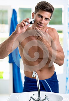 Portrait of man shaving by electric shaver