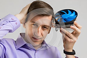 Young man leaned against the head of the cooler from computer isolated on a light background