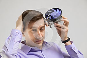 Young man leaned against the head of the cooler from computer isolated on a light background