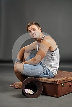 Portrait of a man sitting on a retro suitcase