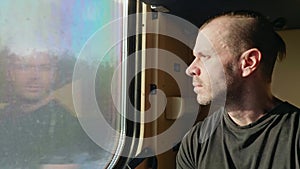 Portrait of a man sitting in a train car and looking out the window.