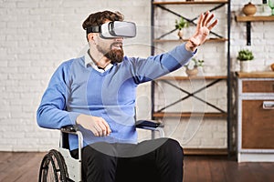 Portrait of a man sitting on a wheelchair and using a VR headset