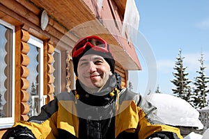 Portrait of man in ski clothes, with ski goggles on his head, sits at table outdoors. skier is resting after skiing, smiling,