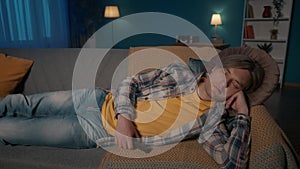 Portrait of a man sleeping on the couch late at night close up. The man fell asleep, holding the remote control in his