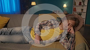 Portrait of a man sleeping on the couch late at night close up. The man fell asleep, holding the remote control in his