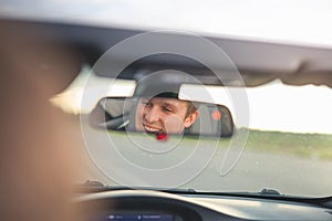 Portrait of man smiling into the car mirror