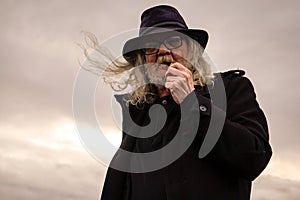 Portrait of man smoking pipe against sky