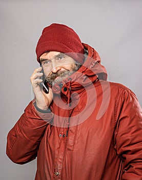 Portrait of man speaking into mobile phone in winter coat freezing in the cold