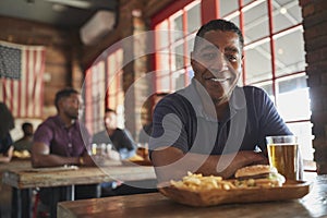 Portrait Of Man In Sports Bar Eating Burger And Fries