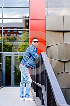 Portrait of a man in a sports suit, a jean jacket, a decorative T-shirt and jeans, a walk around the park and a commercial center photo