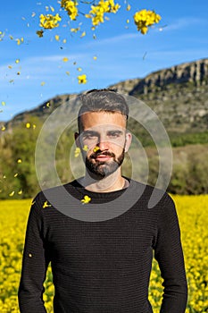 Portrait of a man in springtime in a field of yellow flowers on a sunny spring day