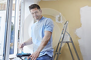 Portrait Of Man Stirring Paint Before Decorating Room At Home