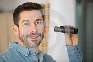 portrait man stood indoors holding binoculars