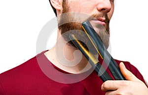 Portrait of man straightened his beard with a straightener, styling his beard on isolated white background